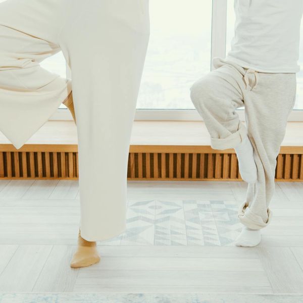 Person meditating peacefully on a yoga mat by a large window.